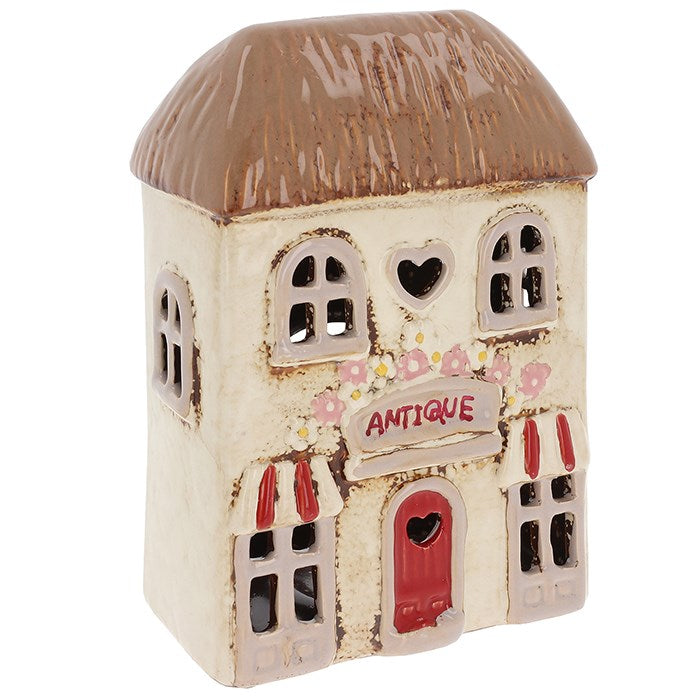 Decorative ceramic house with a brown roof and red door on a white background
