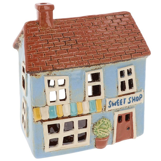 Step into a world of whimsy with this beautifully detailed Village Pottery Sweet Shop Tealight by Shudehill. Part of the beloved collectible village series, this miniature ceramic sweet shop is designed to hold a tealight candle, casting a warm, inviting glow through its charming windows and door.
Hand-painted with delightful pastel tones and intricate details, this piece evokes the nostalgia of a quaint English village sweet shop. Whether you're a collector of Shudehill pottery or simply love adding uniqu