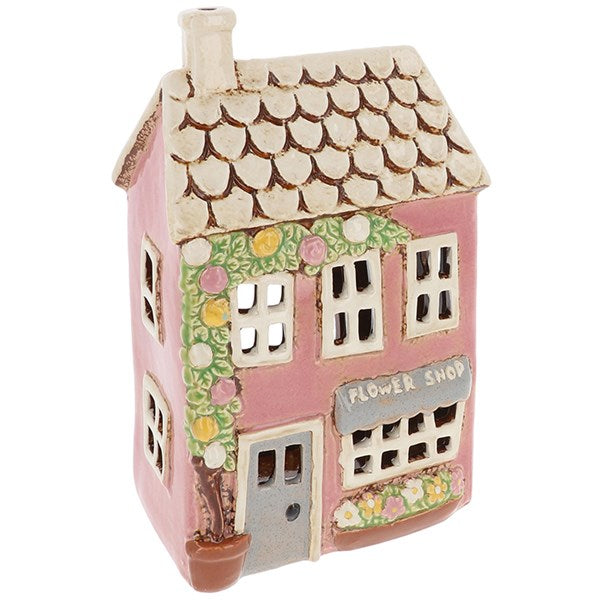 Bring a touch of whimsical charm to your home with the Shudehill Village Pottery Flower Shop Tealight Holder. Expertly crafted with delightful detail, this ceramic tealight holder resembles a quaint English flower shop—complete with potted blooms, painted bricks, and rustic windows.
When lit, the warm glow from within brings the miniature shopfront to life, casting a soft, magical ambience in any room. Perfect for cottagecore lovers, fans of fairy-tale aesthetics, or anyone wanting to add a cosy, nostalgic