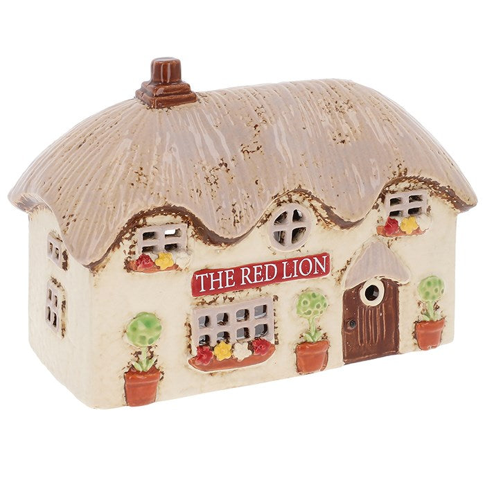 Down a winding cobblestone lane, the Red Lion Pub stands proudly, its windows aglow with the promise of laughter, music, and friendly cheer. The Shudehill Village Pottery Red Lion Pub Tealight Holder (12.5 x 17.5 x 8.3cm) captures this timeless charm in beautifully hand-painted ceramic. Place a tealight inside and watch as a golden radiance spills through the tiny windows, as though merriment stirs within. Perfect for creating a cosy corner, enhancing a seasonal display, or gifting to those who adore the ma