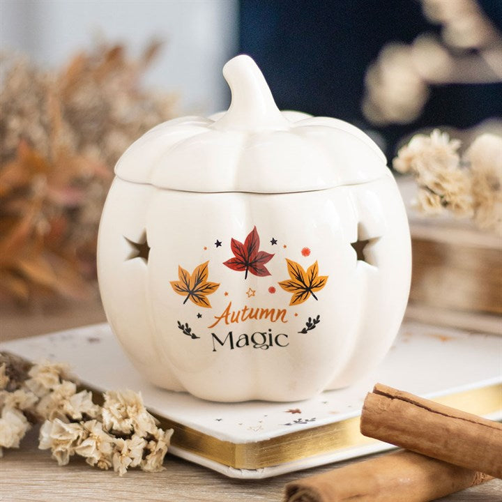 White ceramic pumpkin-shaped container with 'Autumn Magic' text and leaf designs on a wooden surface.
