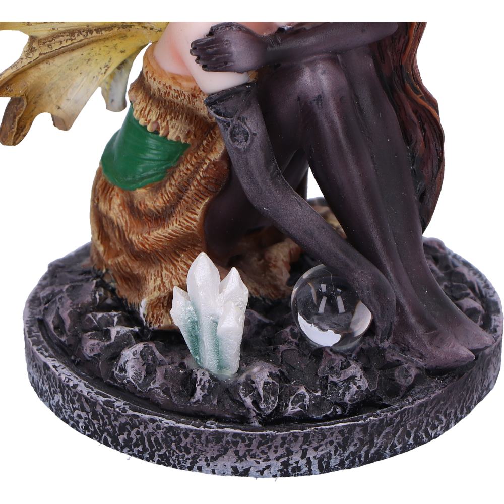 Statue of a fairy with long hair, holding a crystal ball and a crystal, on a dark base.
