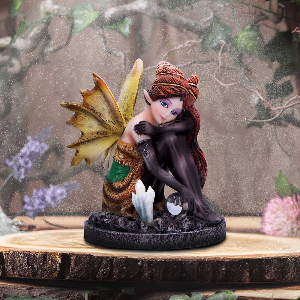 Fairy figurine with wings on a wooden base with a nature-themed background
