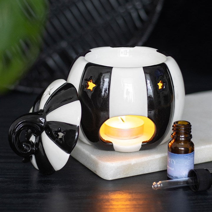 Add some strange and unusual flair to your home with this black and white striped pumpkin oil burner. Perfect for your favourite fragrance oils, this statement piece creates a cosy atmosphere with a touch of the unexpected. Simply place a standard tealight in the back and add your favourite spooky scent to the bowl above. The removable lid completes the design, blending function and style seamlessly. Recommended for use with fragrance oil diluted with water. Always remove the lid whilst in use. Please pract