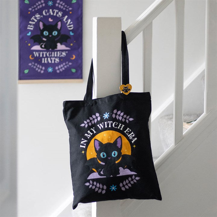 Black tote bag with a cat design and text hanging on a white staircase.