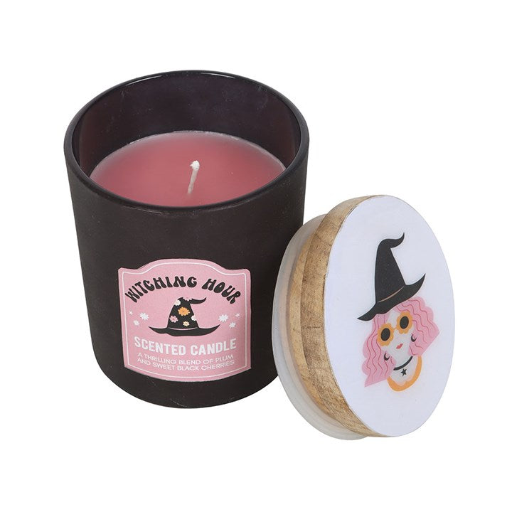 Scented candle in a black container with a pink label, featuring a witch design on a white background.
