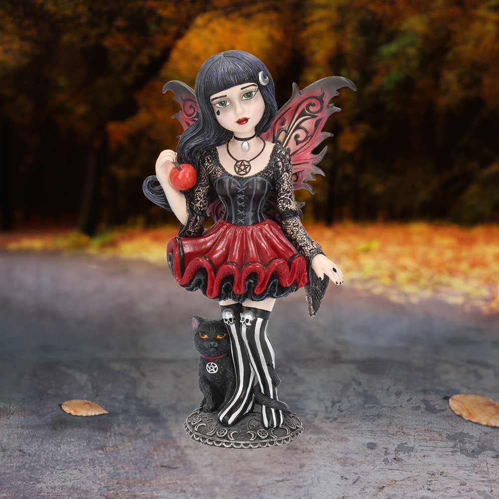 Gothic-style fairy figurine with black hair, red dress, and wings standing on a textured surface with a blurred natural background.