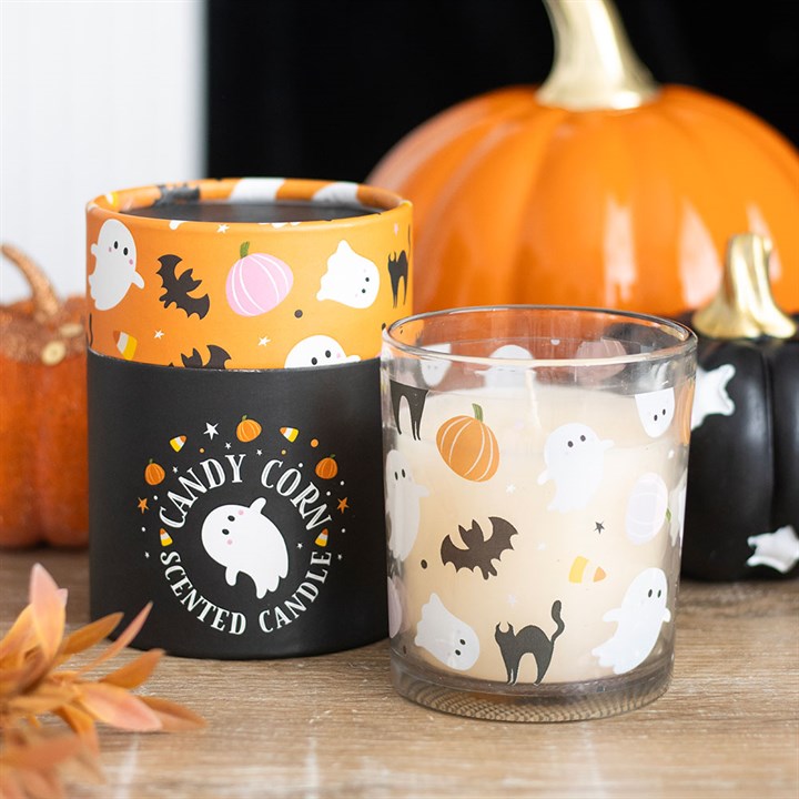 Halloween-themed candle with decorative container and pumpkins in the background