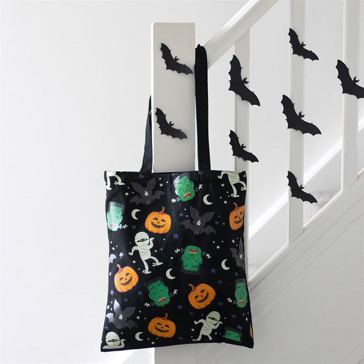 Halloween-themed tote bag with pumpkins, ghosts, and bats on a staircase background.
