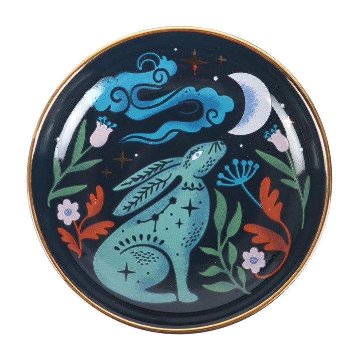 This enchanting Midnight Hare Trinket Dish captures the magic of a moonlit night with its exquisite ceramic design. Featuring a serene hare gazing up at a star-studded sky, the dish is adorned with delicate golden accents that shimmer like hidden spells. Its rounded shape offers a perfect sanctuary for your cherished trinkets, rings, and jewellery, keeping them safe while adding a touch of mystical charm to your altar or dressing table. Embrace the quiet power of the night and let this dish hold your treasu