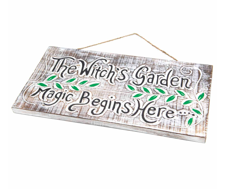 Wooden sign with 'The Witch's Garden Magic Begins Here' text on a white background