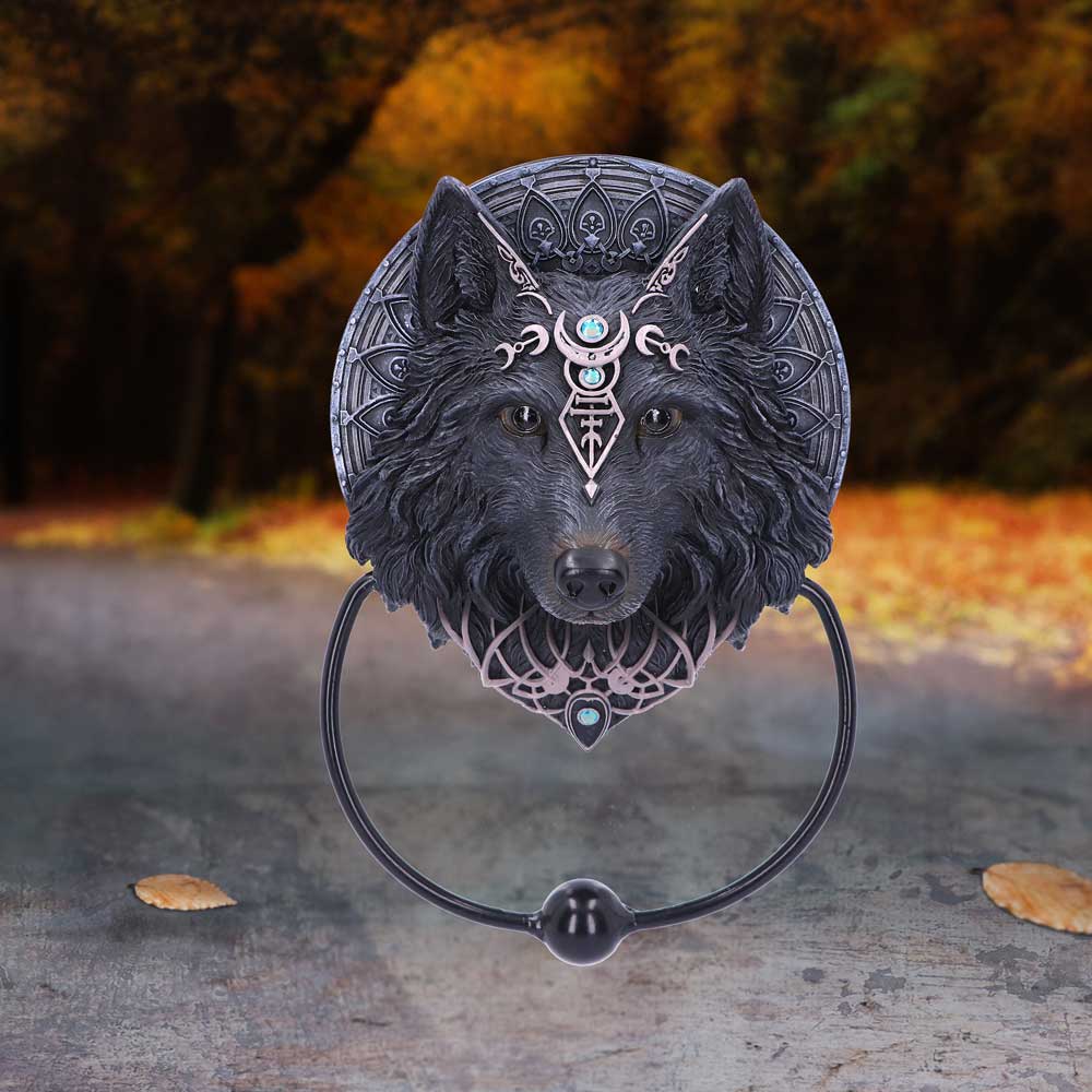 Decorative wolf head with intricate designs on a stand against a blurred natural background