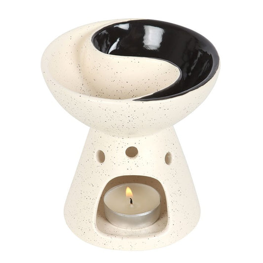 Ceramic oil burner with a lit candle inside on a white background