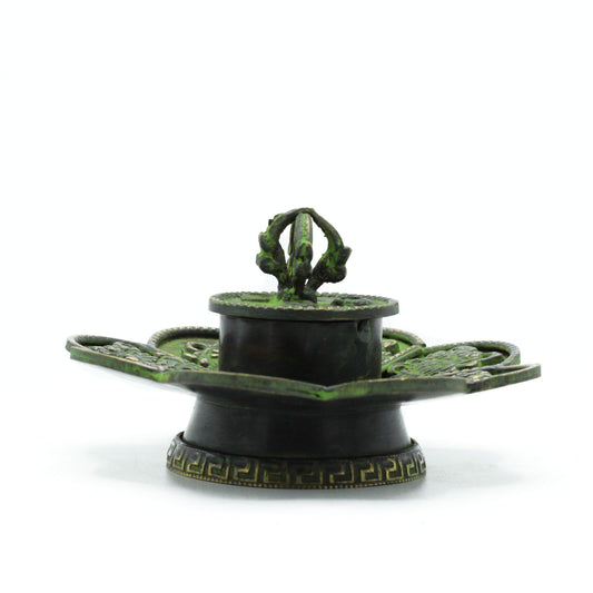 The Eight Auspicious Symbols have long been honored as sacred signs of harmony, balance, and blessing upon the path of spirit. This Brass Verdigris Tibetan Cone & Incense Holder – Eight Symbols is a vessel of serenity, designed not only as an incense burner but as a channel of spiritual energy.
Handcrafted in India, the flower-shaped base is beautifully engraved with the Eight Sacred Emblems, each carrying its own blessing: good fortune, health, prosperity, longevity, peace, harmony, victory, and spiritual