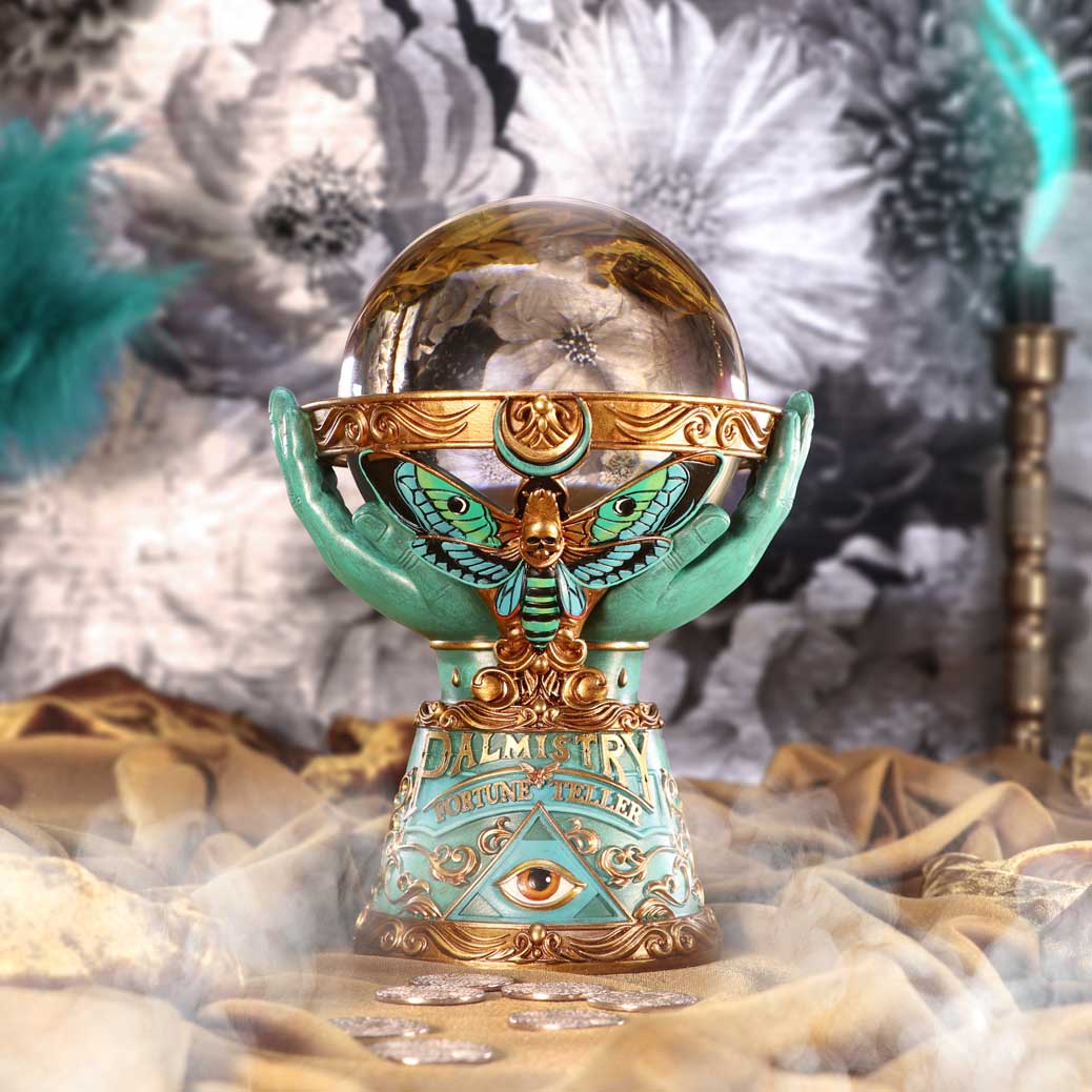 Decorative crystal ball with green and gold base on a textured surface