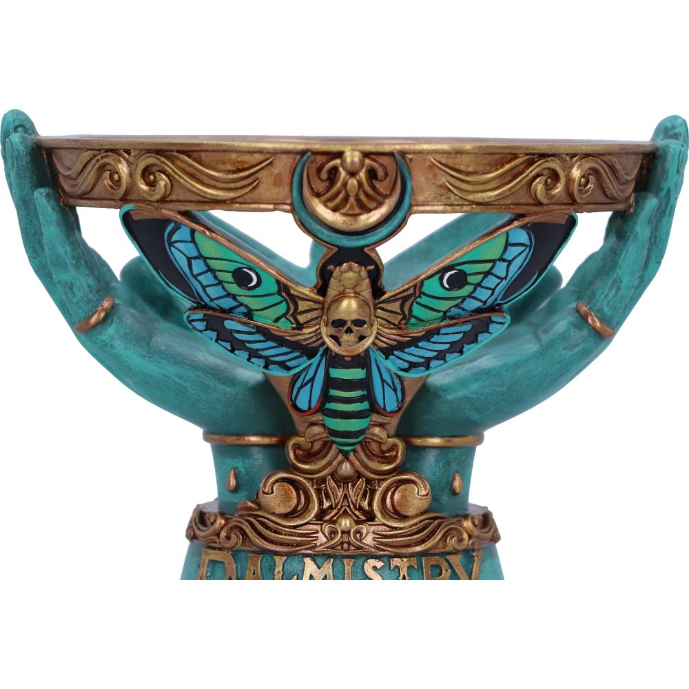 Decorative piece with teal hands holding a butterfly with skull design on a white background