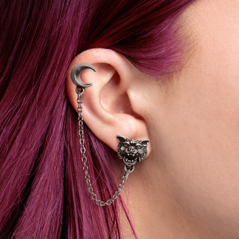 Earring with wolf design and chain detail worn by a person with purple hair