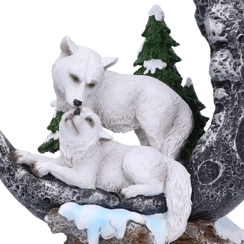 Two white wolf figurines on a branch with a snowy landscape background