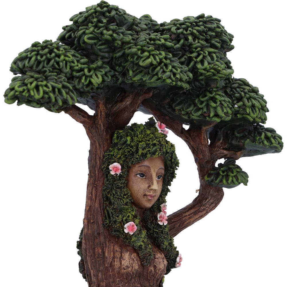 Figurine of a woman with green hair and flowers, surrounded by tree branches and leaves.