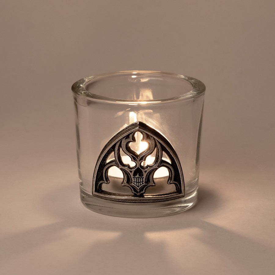 Clear glass candle holder with decorative metal base on a neutral background