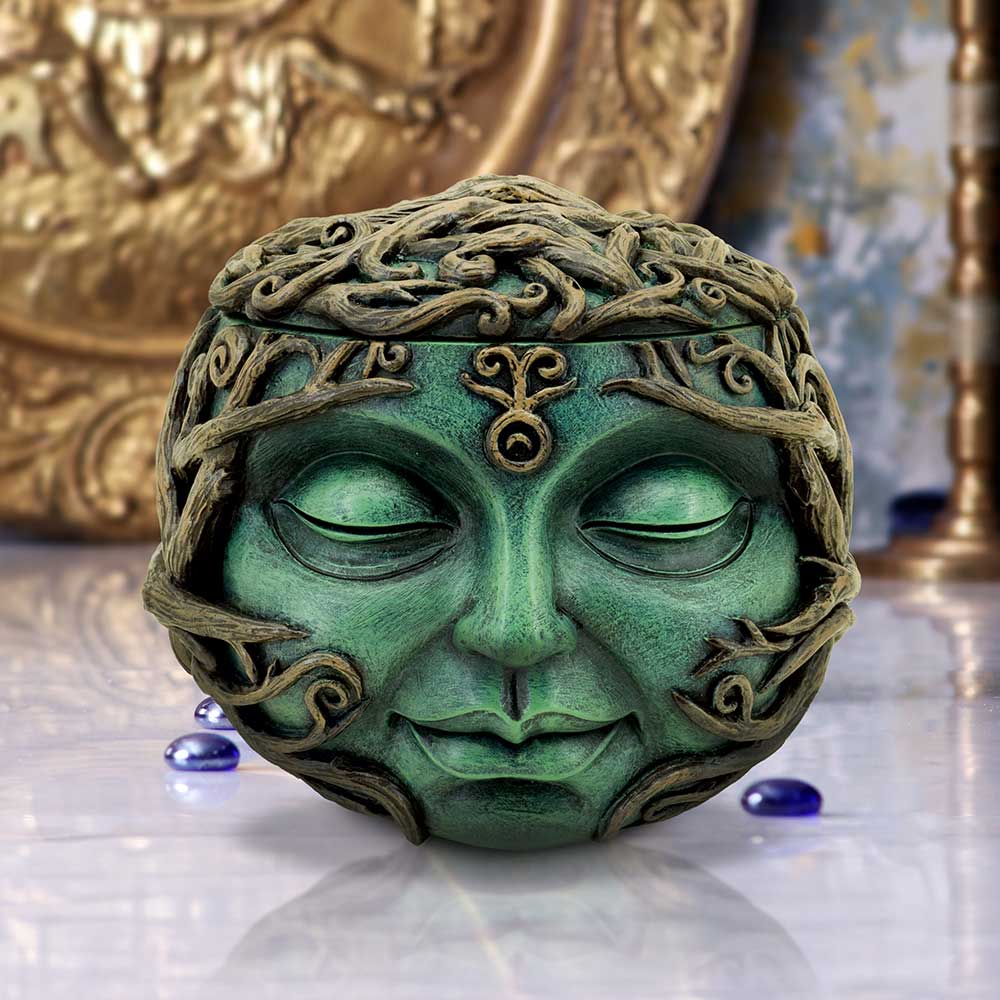 Green stone sculpture of a face with intricate patterns on a reflective surface