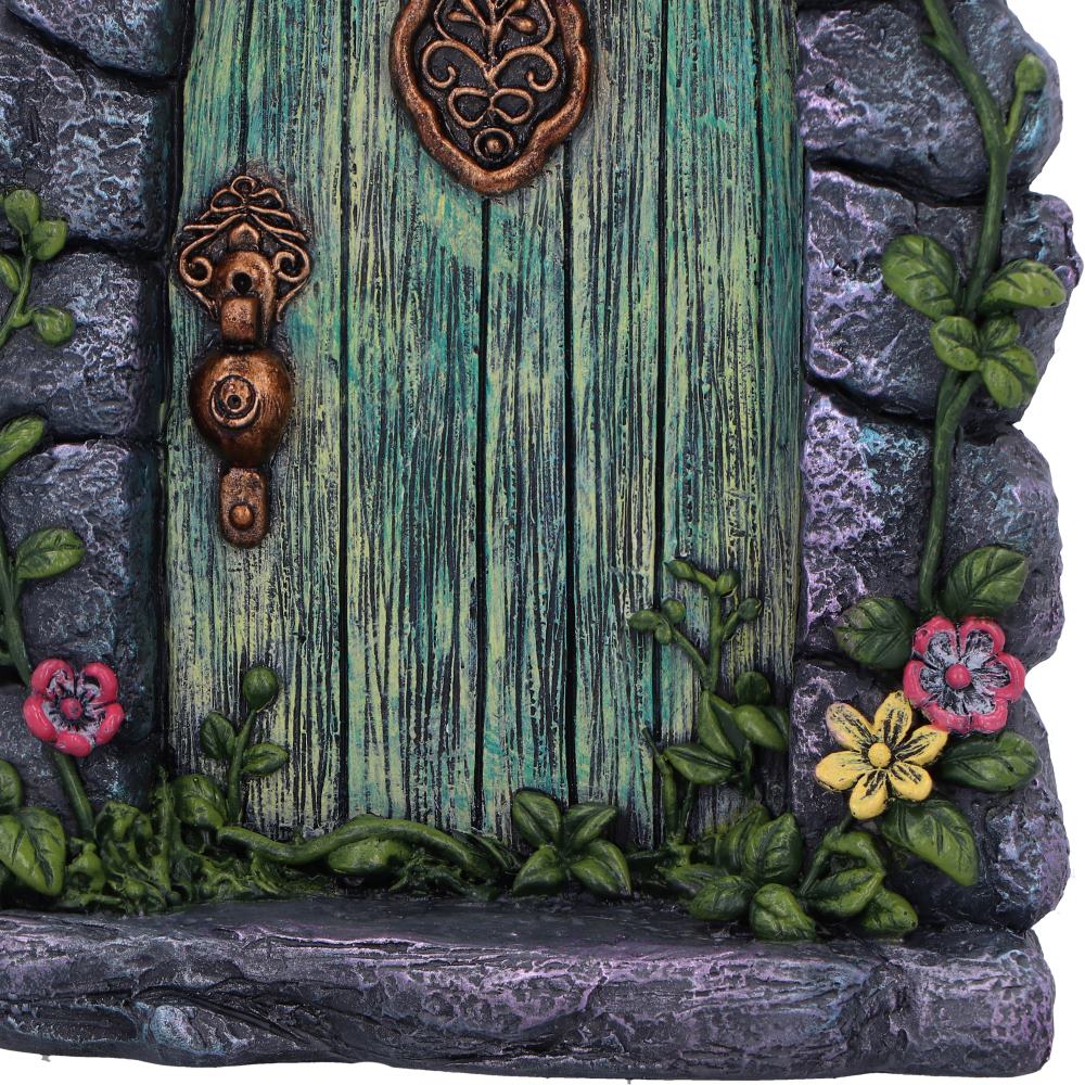 Tread softly, dear wanderer — for you’ve reached the threshold of the fae. The Fae’s Forest Welcome fairy door, standing 16cm tall, invites curious souls to the hidden realms beyond the veil. Nestled within a stone arch, the enchanted green wooden door is adorned with floral brass accents, blooming red and yellow blossoms, and creeping vines that whisper stories of old.
A rustic bronze lock and handle glint beneath the forest light, adding charm and mystery to this magical gateway. Place it at the base of
