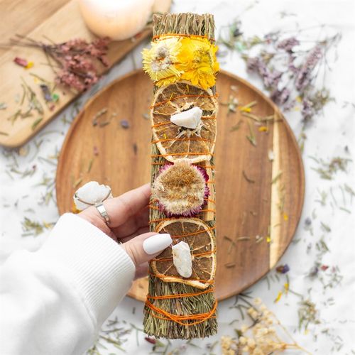 The act of ‘smudging’ is a traditional Native American practice used to cleanse and purify spaces using the smoke of burning sacred herbs. Sustainably sourced and made in the USA, this beautiful ritual wand features fragrant rosemary, palo santo, orange peels, dried flowers and a raw quartz crystal thoughtfully handtied into a tight bundle for burning and display.