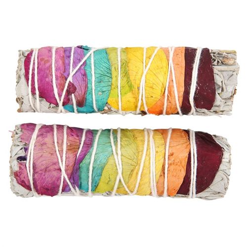 Two rainbow-colored bundles of sage wrapped in white string on a white background