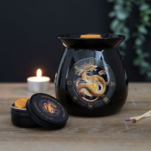 Black wax warmer with dragon design on a wooden surface with a lit candle in the background.