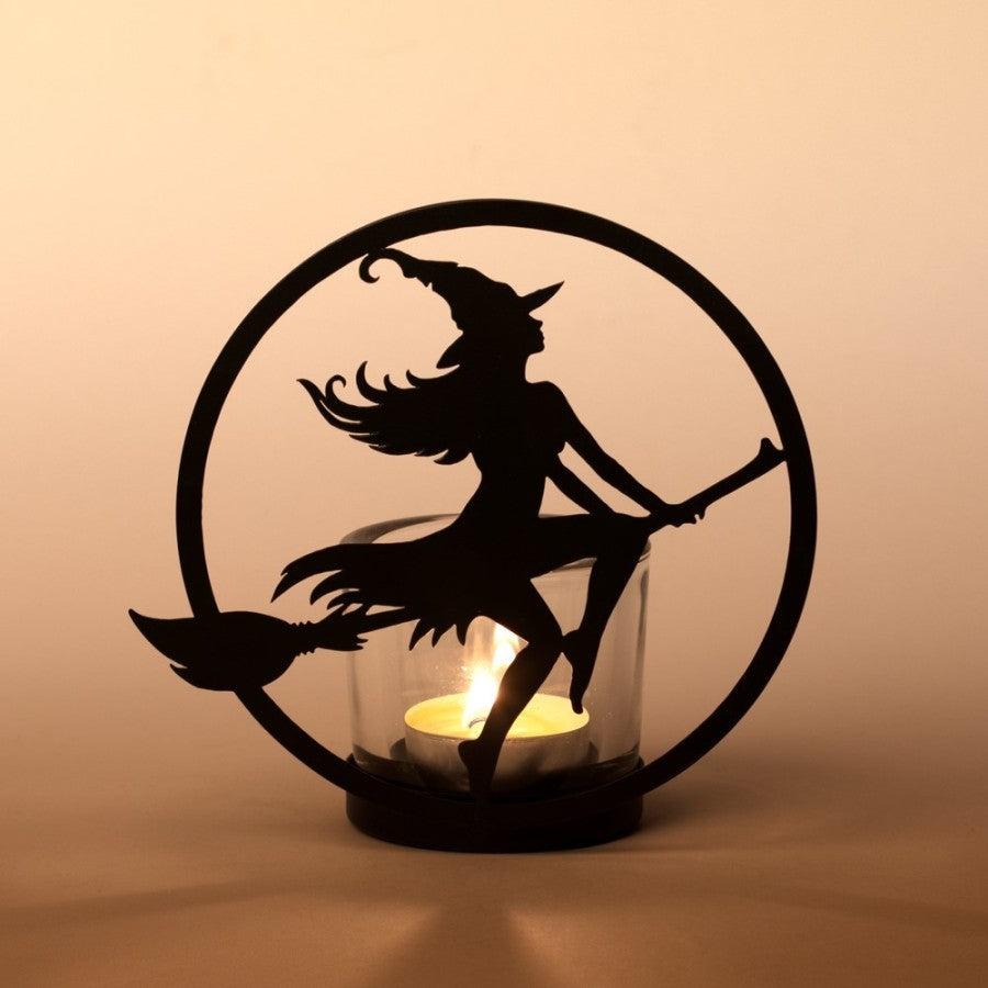 Illuminate your sacred space with the Witch by Moonlight Tealight Holder by Alchemy Gothic. Handcrafted from black-coated iron and shimmering glass, this mystical creation captures the silhouette of a witch soaring across a radiant full moon. As candlelight dances through the glass, it awakens the essence of freedom, transformation, and divine feminine power—a luminous reminder of your own inner witch rising under lunar light.
Perfect for altar adornment, ritual ambience, or as a centrepiece for moon cerem