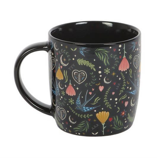 Sip your favourite brew in folk-inspired elegance with the Midnight Bloom Floral Mug, a black ceramic cup adorned with a vibrant all-over Midnight Bloom print. Featuring intricate blossoms in bold, colourful detail, this mug brings a touch of bohemian magic to every moment — from morning rituals to late-night reflections.

With a 350ml capacity, it’s the perfect balance of style and comfort, ideal for your work desk, cosy kitchen, or daily tea and coffee breaks. The contrast between the deep black base and 