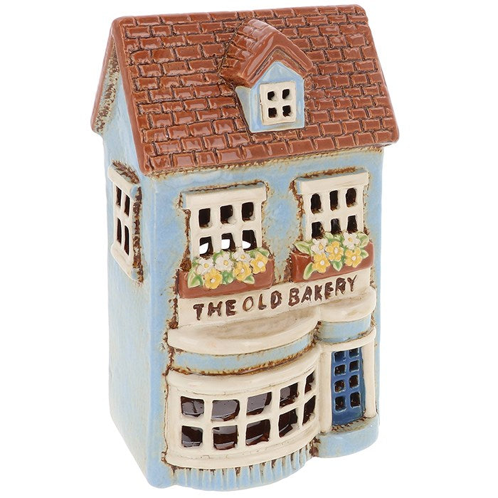 Bring nostalgic charm into your home with the Village Pottery Old Bakery Tealight Holder by Shudehill. This beautifully crafted ceramic tealight holder is designed to resemble a quaint village bakery, complete with rustic details, warm tones, and inviting character. When lit, the soft glow from the windows creates a cozy, welcoming atmosphere reminiscent of old-world charm.

Perfect for mantelpieces, window sills, or as part of a seasonal village display, this delightful tealight holder makes a lovely gift 