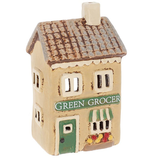 Down a cobbled lane where herbs dry in the summer breeze and apples gleam like drops of sunset, the village greengrocer keeps watch. This finely crafted ceramic tealight holder captures that charm — a little shop of abundance, with painted fruits and vegetables adorning its façade. When a candle flickers within, the windows glow as though the shopkeeper has just lit their lamps to welcome evening customers. Ideal for a witch’s kitchen altar, a harvest celebration, or to bring the spirit of plenty into your 