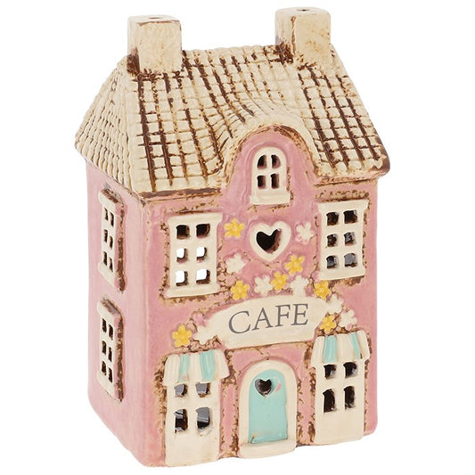 In the heart of the enchanted village, there is a little café where whispers of magic mingle with the scent of freshly brewed tea. This charming Village Pottery Café Tealight Holder by Shudehill Village Pottery captures that very spirit. Crafted with care and rich in rustic detail, it measures 15.5 x 9.5 x 8cm — the perfect size to nestle upon your altar, windowsill, or cosy reading nook. When you place a tealight within, warm light flickers through its tiny windows, casting spellbound shadows across the ro