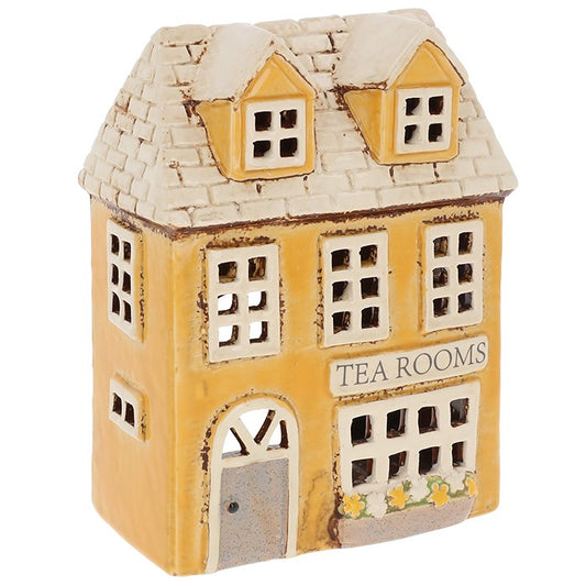 Step into a world where the soft glow of candlelight meets the charm of a storybook village. The Shudehill Village Pottery Tea Rooms Tealight House (19 x 14 x 8cm) is a delightful ceramic creation, painted in warm, inviting hues and detailed with the quaint elegance of an old-fashioned tea shop. When a tealight is placed within, golden light spills from its windows, casting gentle shadows that feel like whispers from a fairy-tale lane. Perfect for cosy evenings, seasonal displays, or as a whimsical gift for