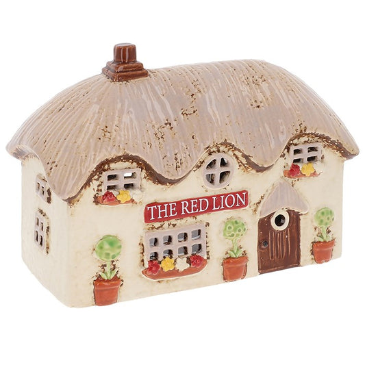 Down a winding cobblestone lane, the Red Lion Pub stands proudly, its windows aglow with the promise of laughter, music, and friendly cheer. The Shudehill Village Pottery Red Lion Pub Tealight Holder (12.5 x 17.5 x 8.3cm) captures this timeless charm in beautifully hand-painted ceramic. Place a tealight inside and watch as a golden radiance spills through the tiny windows, as though merriment stirs within. Perfect for creating a cosy corner, enhancing a seasonal display, or gifting to those who adore the ma