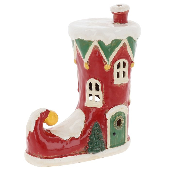 Step into a world of festive enchantment with the Village Pottery Christmas Elf Boot House Tealight Holder, a handcrafted ceramic creation that captures the joyful spirit of the season. Shaped like a cheerful elf’s boot transformed into a cosy little house, this charming tealight holder radiates warmth and whimsy.

When a tealight is placed inside, its soft golden glow shines through the tiny windows, illuminating the snowy details and playful design. Each piece is lovingly made in the signature Village Pot