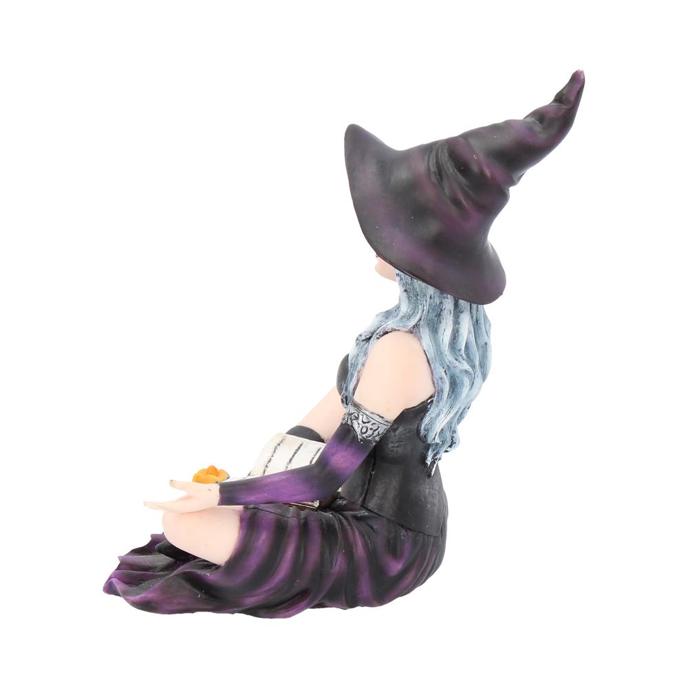 Sculpture of a witch in a purple dress and hat holding a pumpkin on a white background