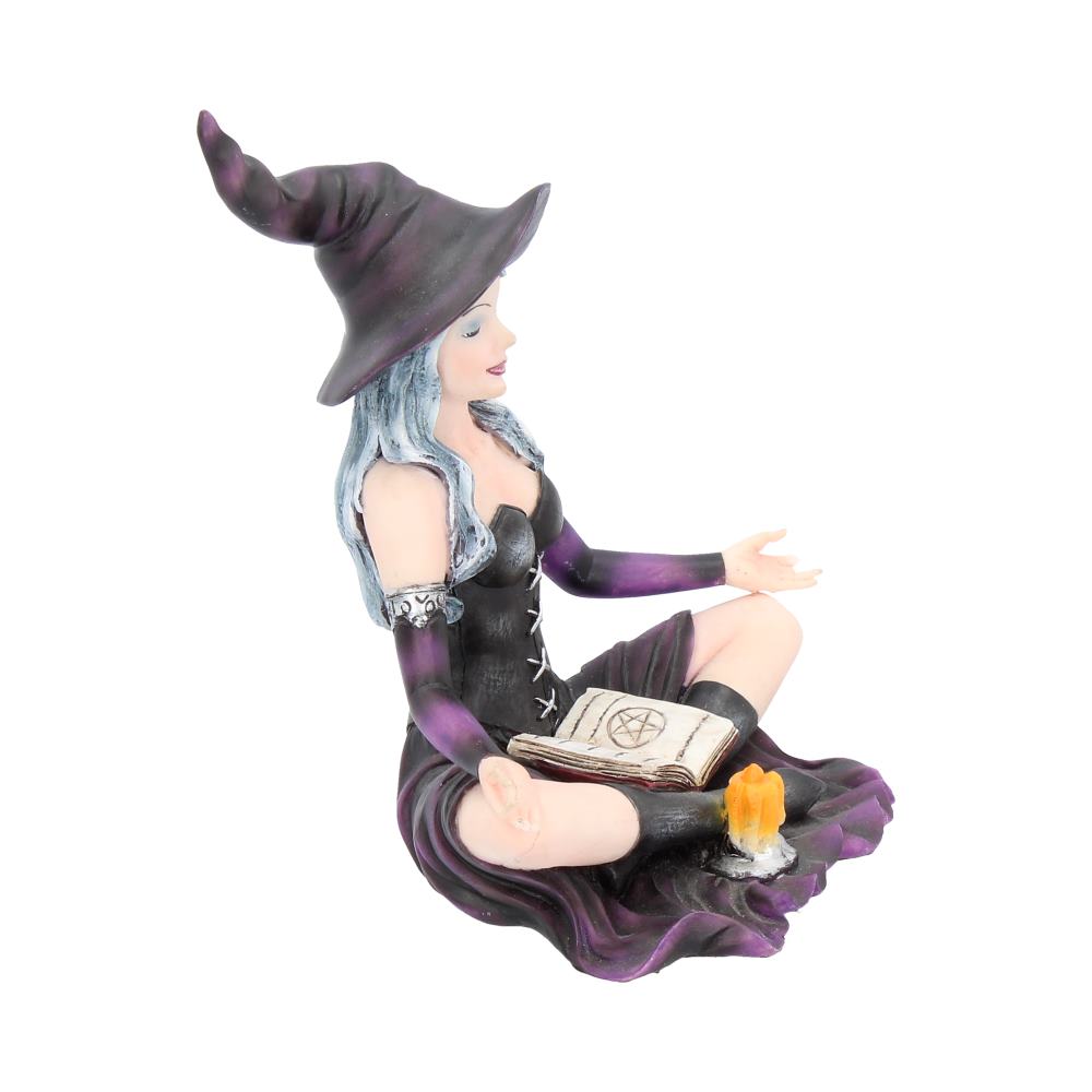 Witch figurine with a book and candle on a white background