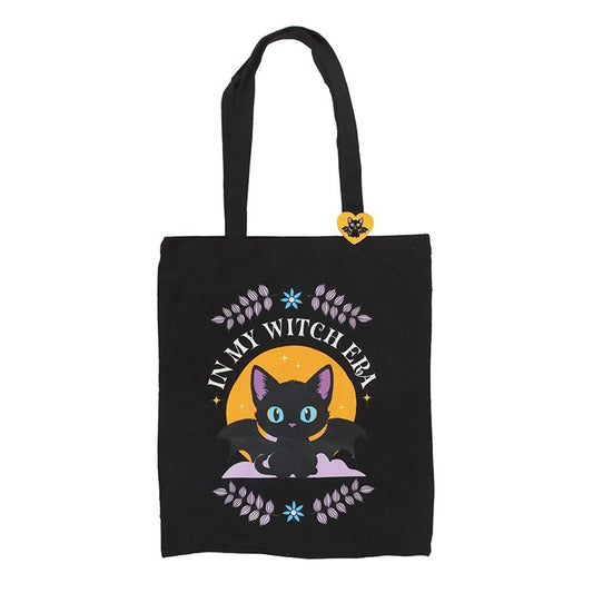 Step out in spooky style with this polycotton tote bag featuring the phrase ‘In My Witch Era’ alongside an enchanting bat-winged black cat. Complete with a matching enamel pin, it’s the perfect everyday accessory for those who love all things mystical.