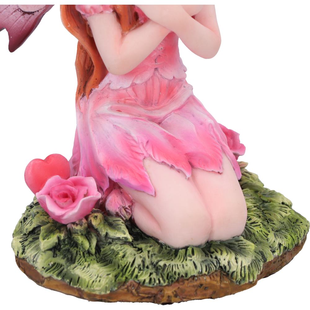 Fairy figurine with pink dress and red hair on a green base with a heart and rose.