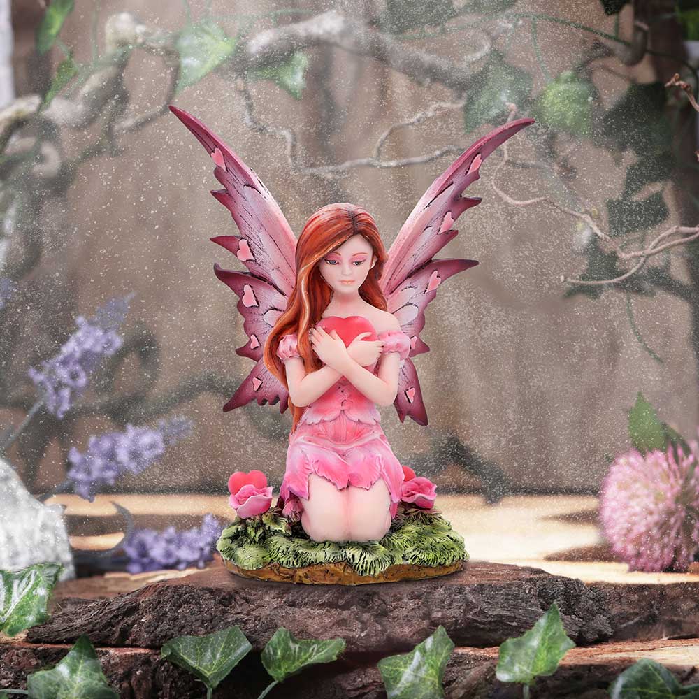 Pink fairy figurine with red hair and wings on a natural background
