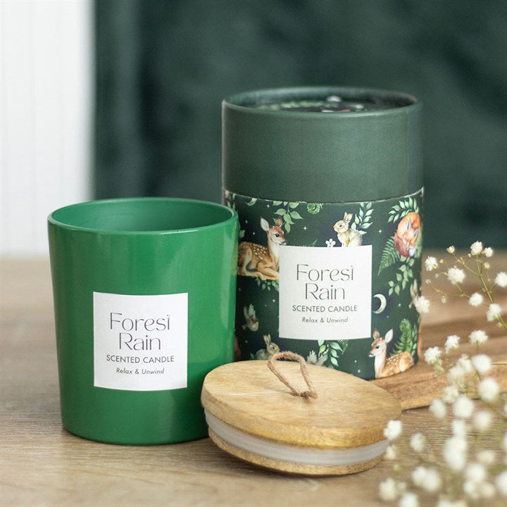 Green 'Forest Rain' scented candle with packaging on a wooden surface.