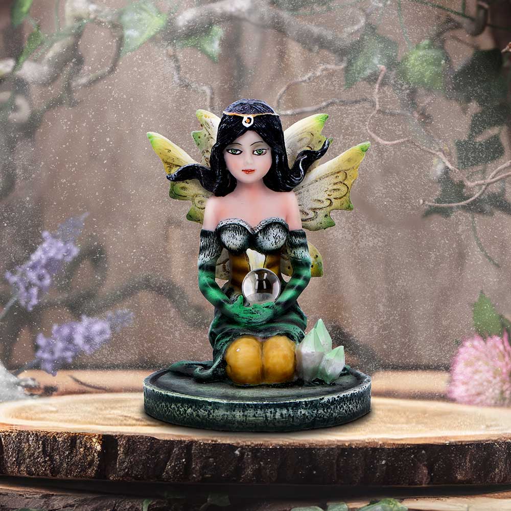Fairy figurine with green dress and wings on a wooden base with a nature-themed background