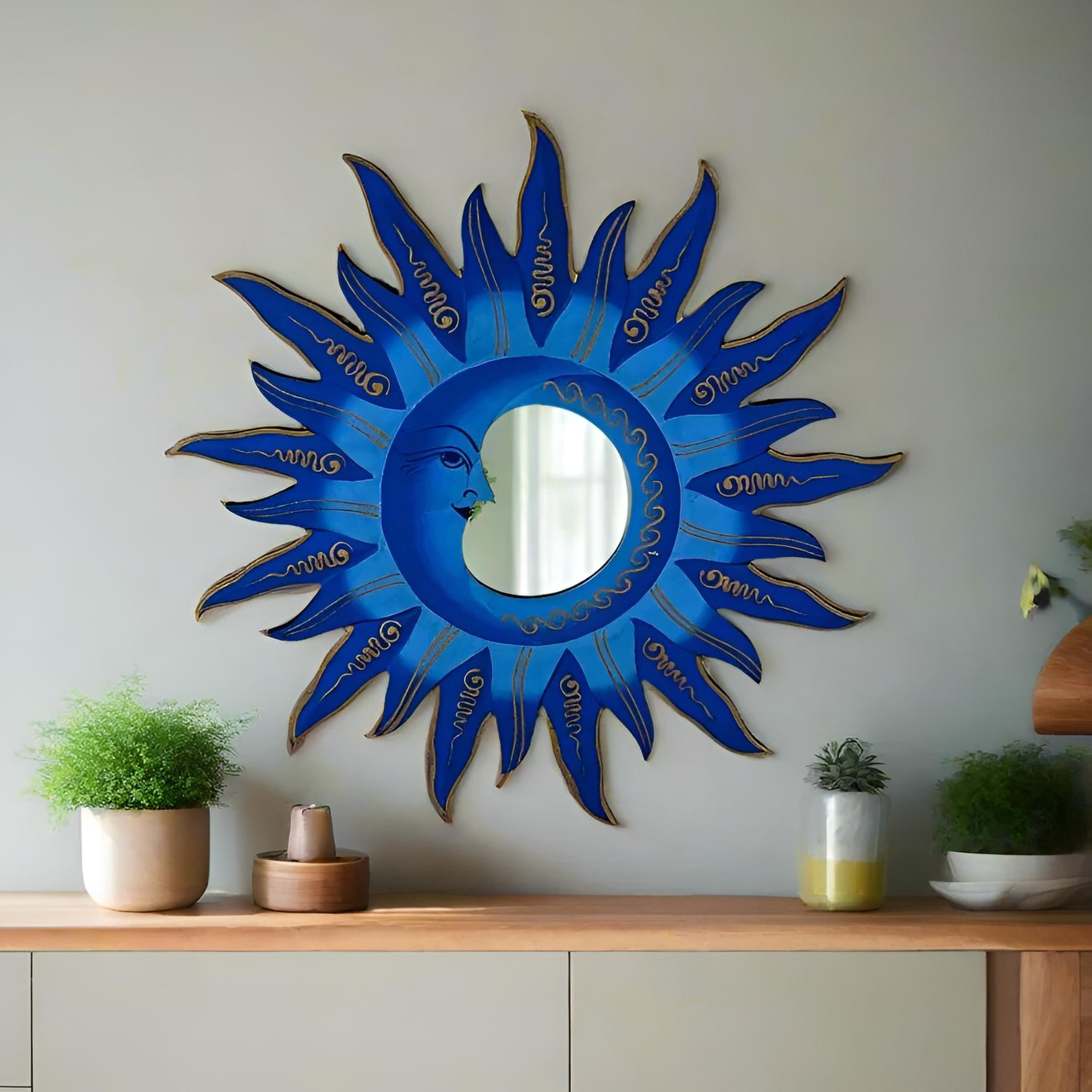 Decorative blue sun-shaped mirror on a wall above a wooden shelf with plants.