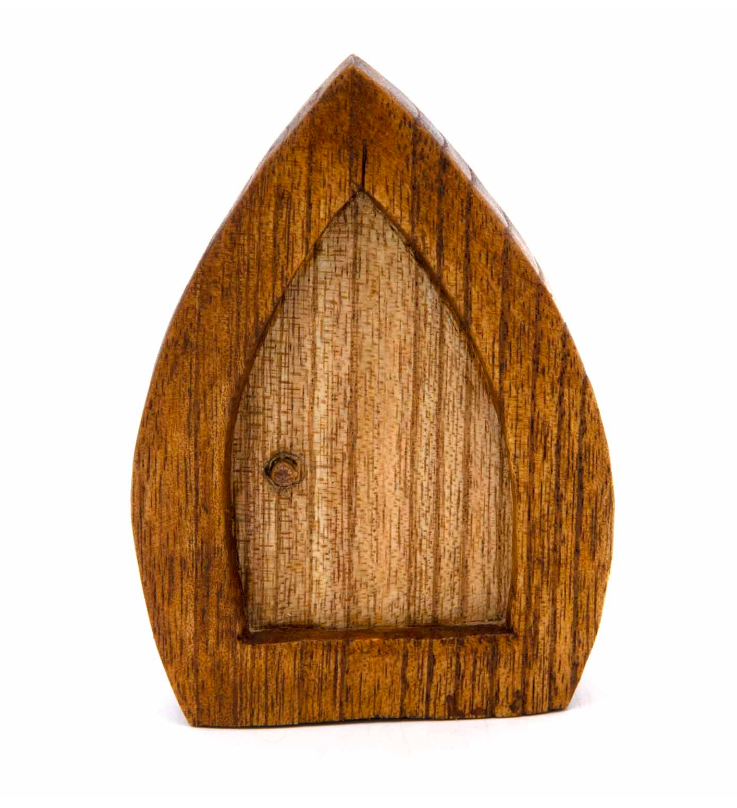 Step into the magic of folklore and woodland enchantment with this Fairy Door Woodcarving, lovingly handcrafted in Bali. Measuring approximately 10 x 7 x 2cm, this whimsical piece is carved from natural wood and shaped to resemble a tiny portal to the fae realm — a doorway between worlds where nature spirits dwell.

Each door carries the charm of traditional craftsmanship, its rustic finish and organic detailing evoking stories of forest guardians and hidden folk. Perfect for altars, gardens, and bohemian h