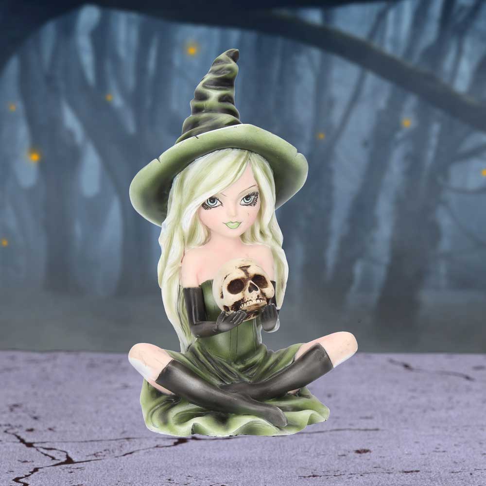 Figurine of a witch with a skull in a forest setting