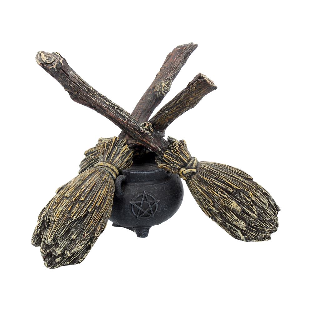 Decorative item with brooms and a black cauldron featuring a pentacle symbol on a white background