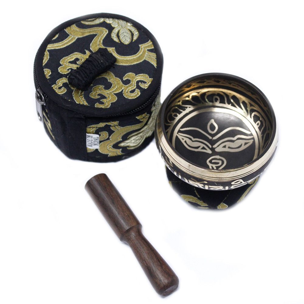 Tibetan singing bowl set with black and gold design, wooden striker, and carrying case on a white background