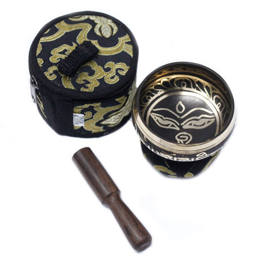 Tibetan singing bowl set with black and gold design, wooden striker, and carrying case on a white background